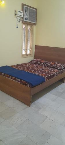 a wooden bed in a room with a window at Al Amoodi Furnished Apartments in Hyderabad