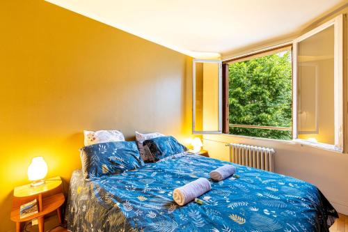 une chambre avec un lit avec des draps bleus et une fenêtre dans l'établissement En face de Paris, les arbres, à Saint-Maurice