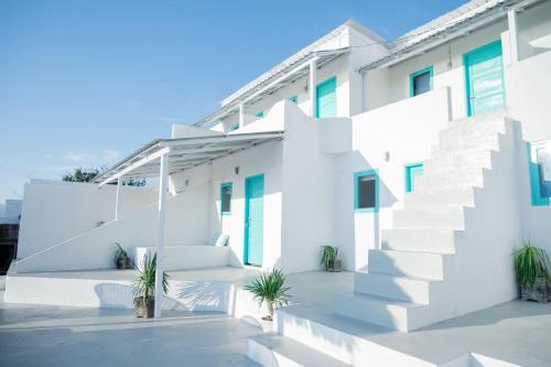 a white house with white stairs and potted plants at Woywoy Paradise in Bira