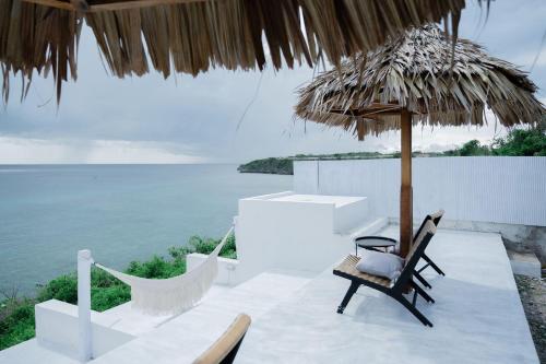 a table with two chairs and a straw umbrella at Woywoy Paradise in Bira