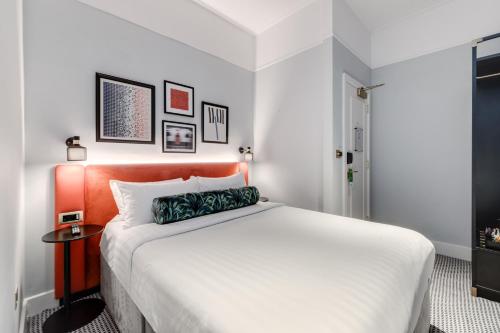 a bedroom with a large bed with an orange headboard at Mornington Hotel London Kensington, BW Premier Collection in London