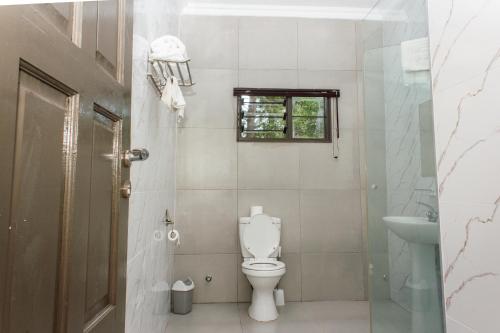 łazienka z toaletą, umywalką i oknem w obiekcie Cedar Place w mieście Blantyre