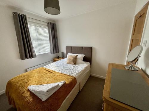 1 dormitorio con cama, escritorio y espejo en Swallows Cottage Coniston, en Coniston
