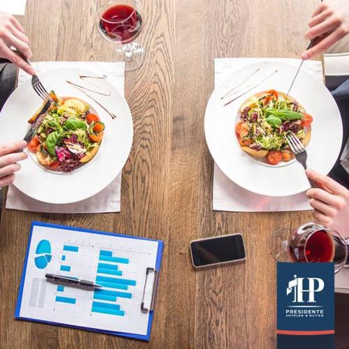 two plates of food on a wooden table with two people eating at Hotel Presidente in Santiago