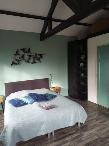 een slaapkamer met een bed met witte lakens en blauwe kussens bij Bed and Breakfast Bianca in Standdaarbuiten