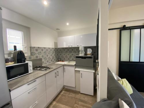 une petite cuisine avec des armoires blanches et un micro-ondes dans l'établissement LE PATIOT 2, à Six-Fours-les-Plages