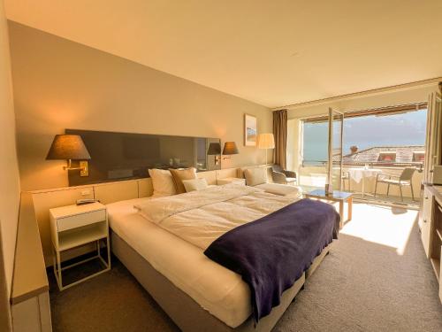 a bedroom with a large bed and a balcony at Seehotel Riviera at Lake Lucerne in Gersau