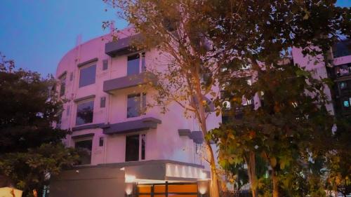 un edificio rosa con árboles delante de él en Hsquare Hotel Andheri West, en Bombay