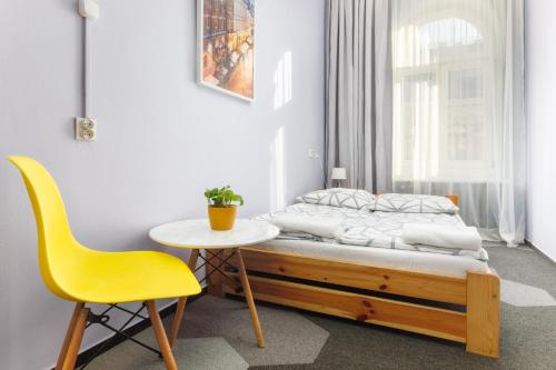 a bedroom with a bed and a table and a yellow chair at Moon Hostel Warszawa in Warsaw