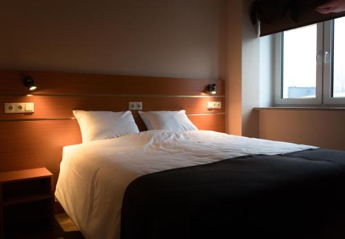 a bedroom with a bed with white sheets and a window at SPA Hotell Peetrimõisa Villa in Viljandi