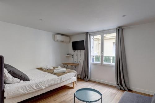 a small bedroom with a bed and a window at 135 Suite Franck - Charmant Studio à Paris in Paris