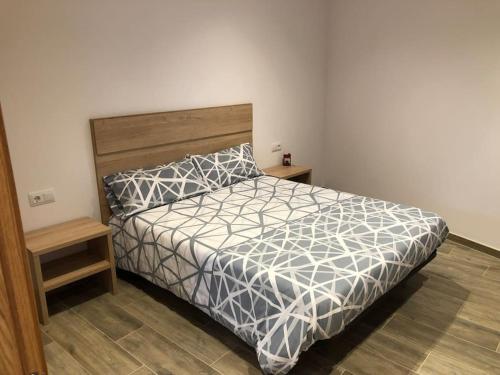 1 dormitorio con 1 cama con edredón gris y blanco en Can Moi - L'Erbera en Molló