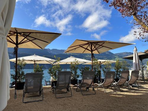 a group of chairs and umbrellas in front of the water at Seehotel Riviera at Lake Lucerne in Gersau