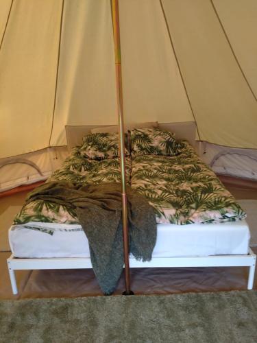 a bed in a tent with a blanket on it at Ruustinnan telttamajoitukset in Saarijärvi