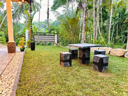 a picnic table and stump benches in a yard at Serene Bliss Villa in Unawatuna
