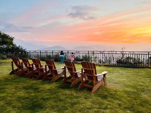 a row of chairs sitting in the grass at sunset at Junyi Landscape Villa in Renai