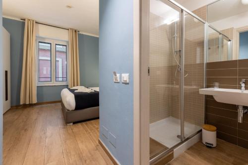 a bathroom with a shower and a sink and a bed at La Loggia de' Banchi in La Spezia