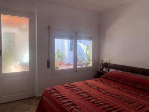 1 dormitorio con cama roja y ventana en Casa frente al mar en Villaricos, en Villaricos