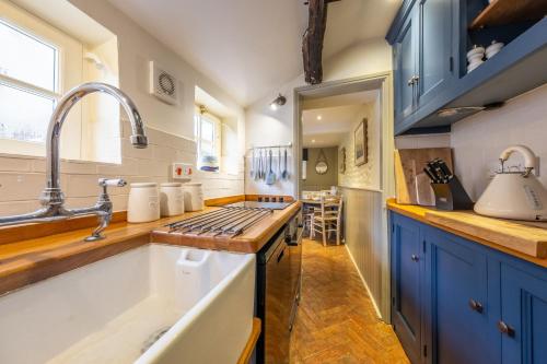 a kitchen with blue cabinets and a sink at Yew Tree Cottage in Blakeney