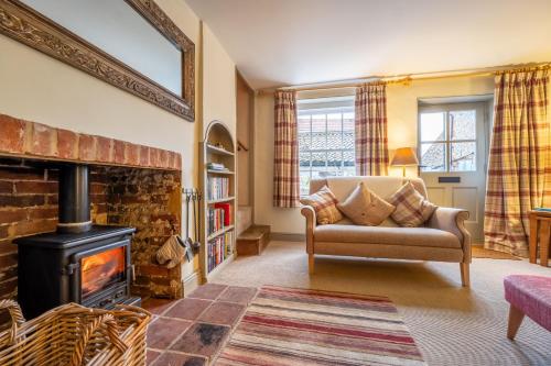 - un salon avec un canapé et une cheminée dans l'établissement Yew Tree Cottage, à Blakeney