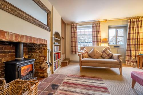 a living room with a couch and a fireplace at Yew Tree Cottage in Blakeney