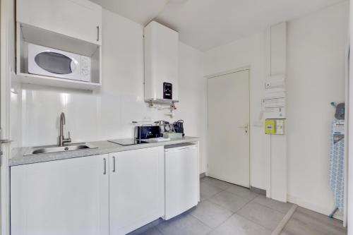 a white kitchen with a sink and a microwave at 807 Suite Cosy - Superb Apartment in Bagnolet