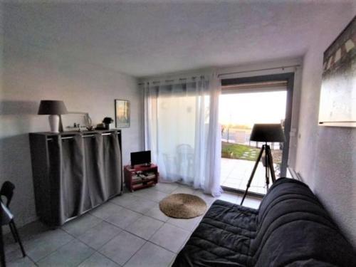 un salon avec un canapé et une grande fenêtre dans l'établissement Studio front de mer - 8150, à Soulac-sur-Mer