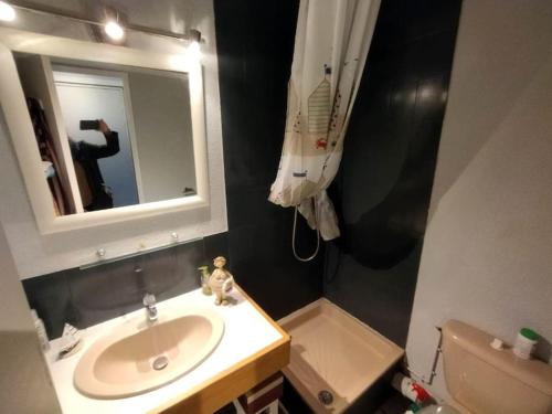 une salle de bains avec un lavabo et une personne prenant une photo dans l'établissement Studio front de mer - 8150, à Soulac-sur-Mer