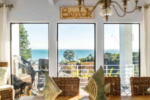 a dining room with a view of the ocean through windows at Summer Beach House in Summerland