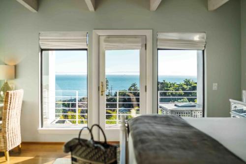 a bedroom with two windows and a view of the ocean at Summer Beach House in Summerland