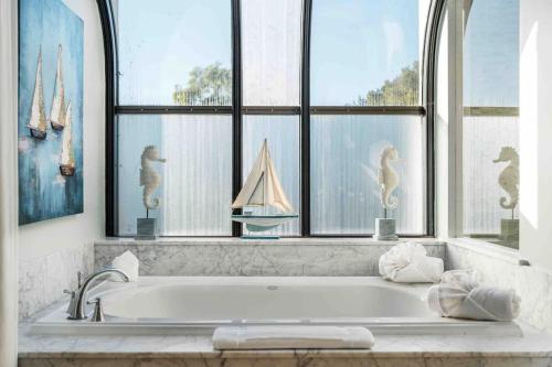 a bath tub in a bathroom with windows at Summer Beach House in Summerland