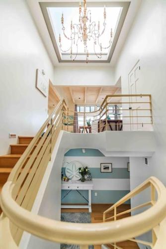a staircase in a house with a chandelier at Summer Beach House in Summerland