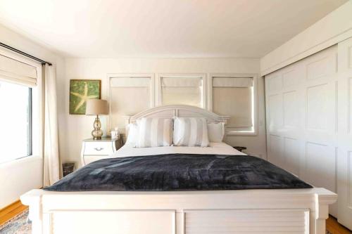 a white bedroom with a large white bed with pillows at Summer Beach House in Summerland