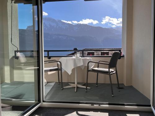a table and chairs on a balcony with a view of mountains at Seehotel Riviera at Lake Lucerne in Gersau