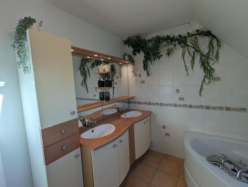 y baño con 2 lavabos, bañera y espejo. en TY FLOSQUE - Jolie maison familiale proche plage, en Ploudalmézeau