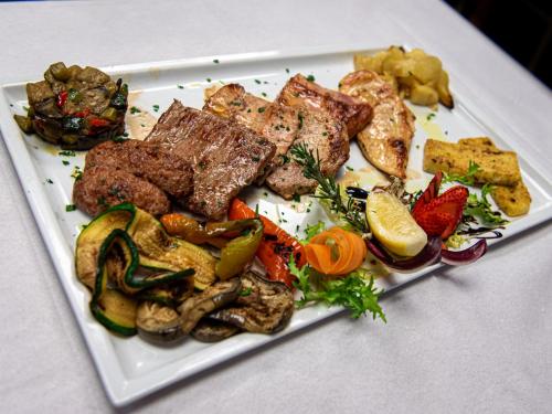a plate of food with meat and vegetables on a table at Biker Hotel Al Gallo Forcello in Passo Pramollo