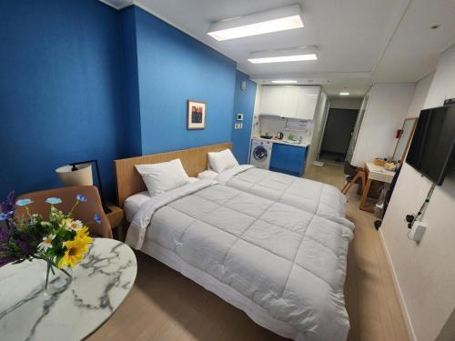 a bedroom with a large bed and a blue wall at Haeundae Bada Residence in Busan