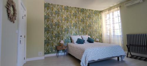 a bedroom with a bed with a floral wallpaper at Domaine les Garrigues in Puygaillard-de-Quercy