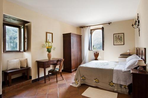 een slaapkamer met een bed, een bureau en 2 ramen bij Abbazia San Pietro In Valle in Ferentillo