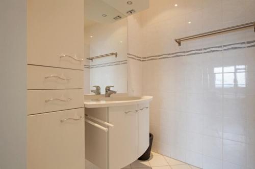 une salle de bain blanche avec lavabo et douche dans l'établissement Sterflat 199, à Egmond aan Zee