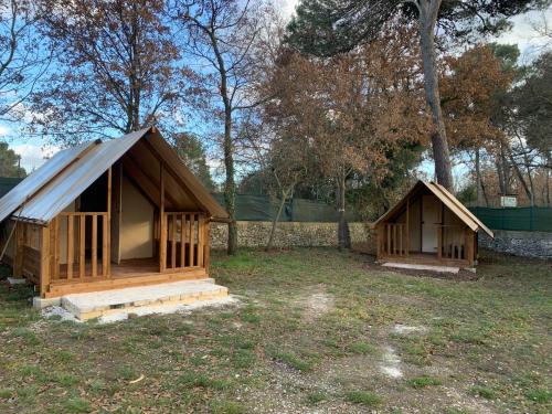 two small wooden shelters in a field with trees at Villaggio Camping Bosco Selva in Alberobello
