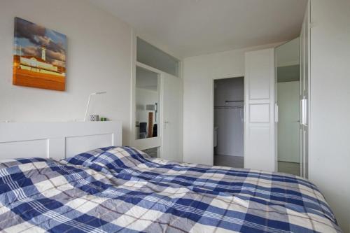 - un lit bleu et blanc dans une chambre blanche dans l'établissement Sterflat 199, à Egmond aan Zee