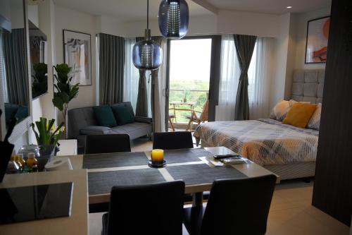 Dominiks Stylish Resort Gem Ocean View Pool Queen Bed at Tambuli 8 Floor Fast Wifi في Maribago: غرفة معيشة مع سرير وطاولة مع كراسي