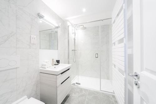 a white bathroom with a shower and a sink at Urban Chic – Drury in London