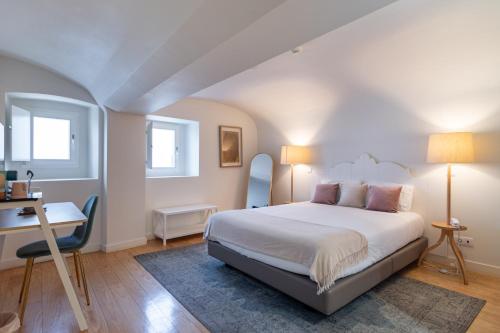 a bedroom with a bed and a desk and windows at Templo Boutique Hotel in Évora