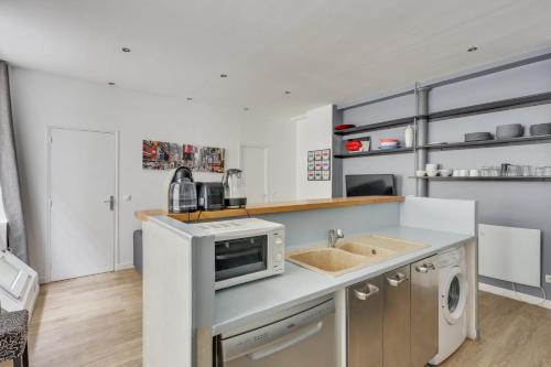 a kitchen with a sink and a microwave at 163 Suite Carole - Superb apartment in Paris in Paris
