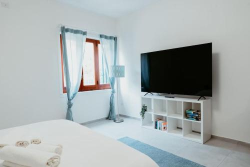 - une chambre blanche avec une télévision à écran plat dans l'établissement La Casa In Campagna, à Pouzzoles