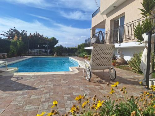 a chair sitting on a patio next to a swimming pool at ROSE VILLA - 3 BED POOL in Episkopi Limassol