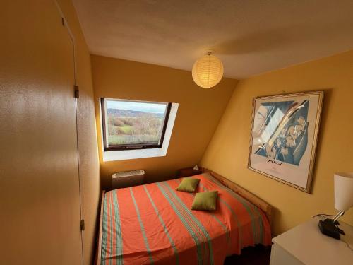 um pequeno quarto com uma cama e uma janela em L'Horizon em Villers-sur-Mer