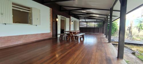 een veranda met een houten vloer en een tafel en stoelen bij La Villa des Palmiers Bleus - Piscine & Jardin in Matoury